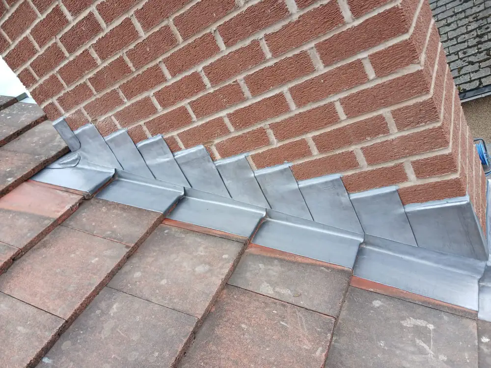 New lead flashing installed around a brick chimney