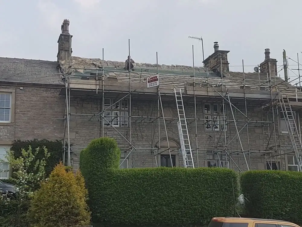 Heritage slate roof work on a stone house with scaffolding
